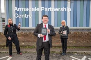 New Library app launch Neighbourhood Manager Anne-Marie Vance, Councillor Andrew McGuire and Customer Service Assistant Rachael Ferguson hold up devices outside Armadale library